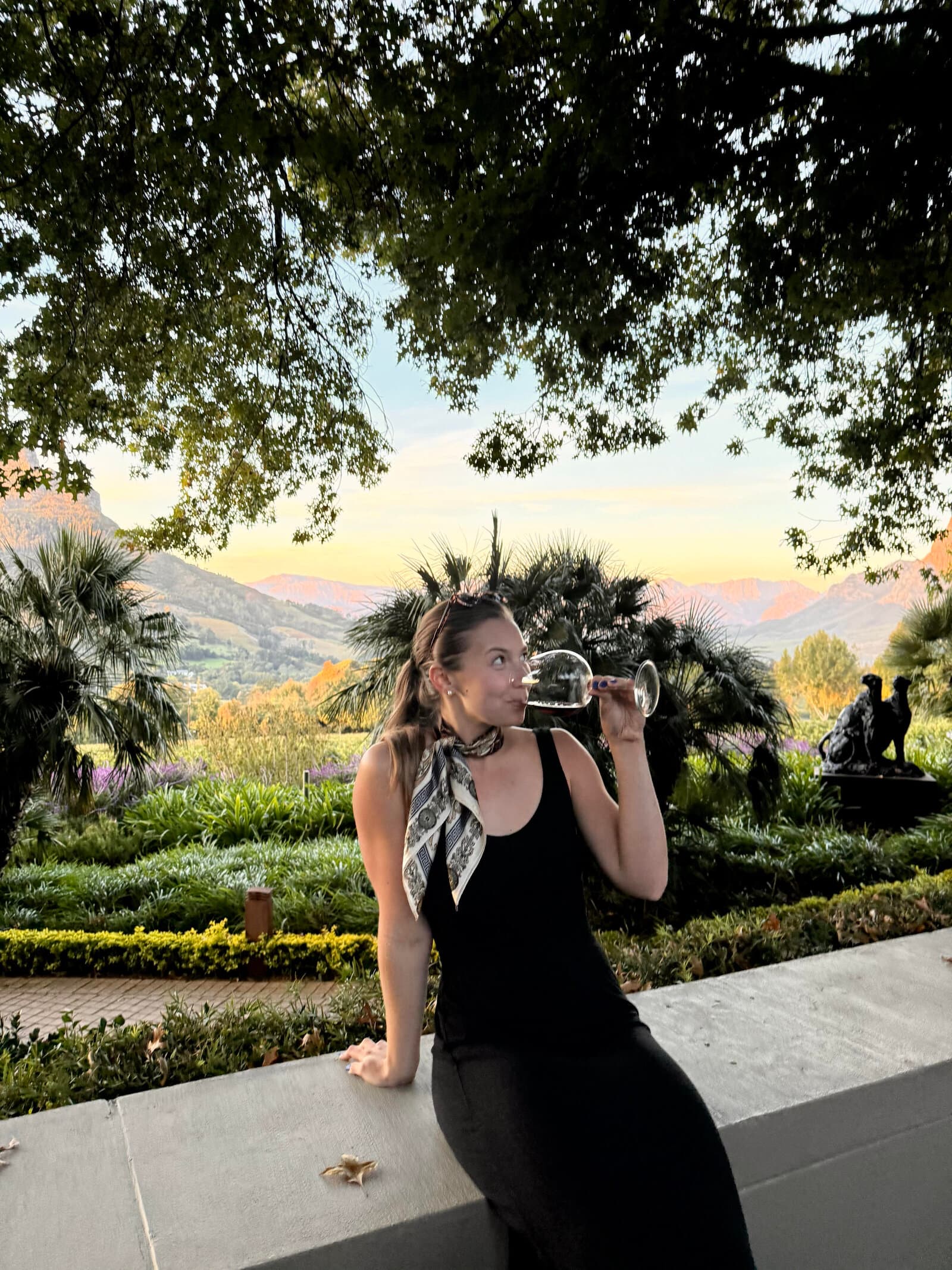 Madison drinking wine in a garden at golden hour
